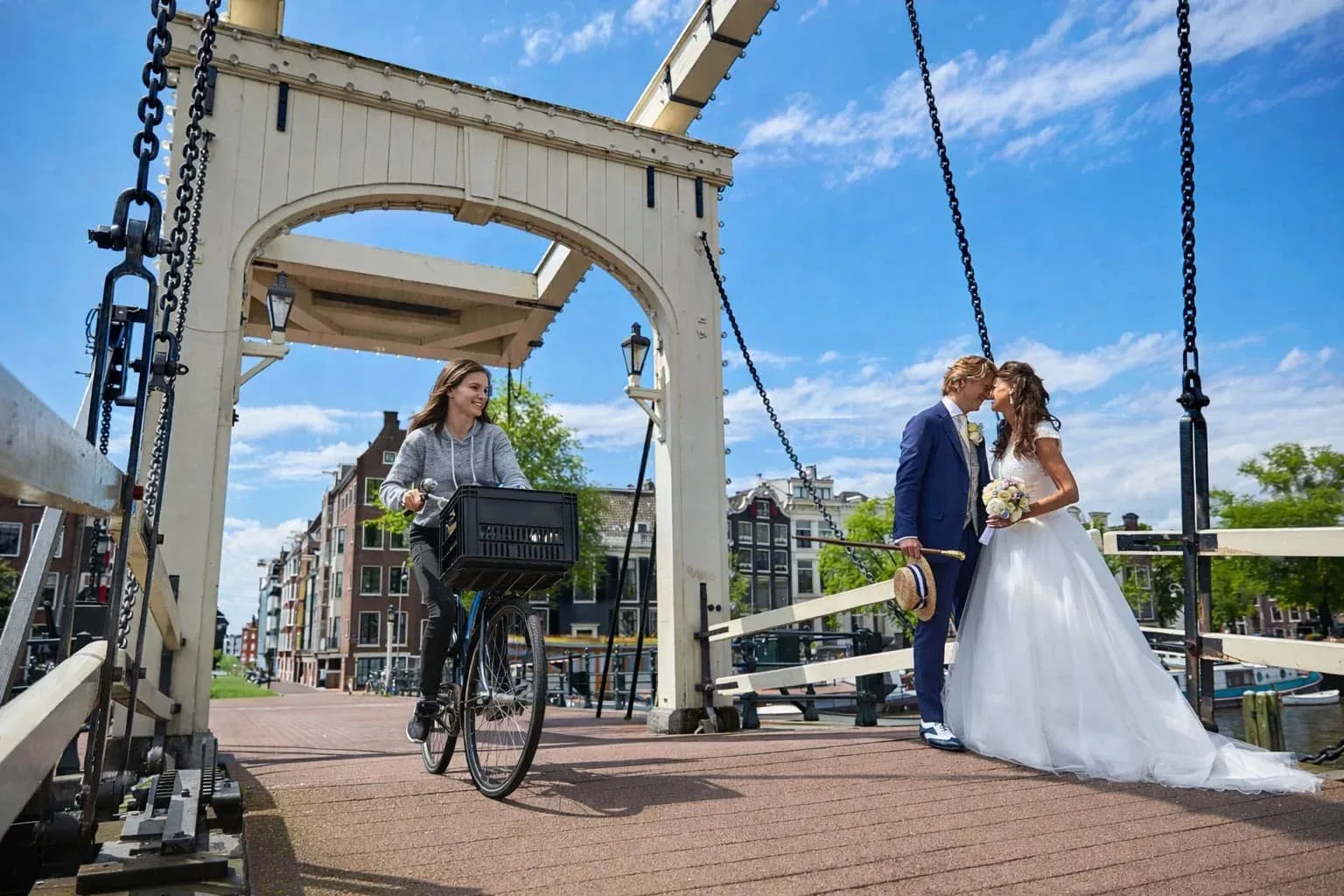 Bruidspaar op de Magere Brug in Amsterdam, terwijl er een meisje voorbij fietst