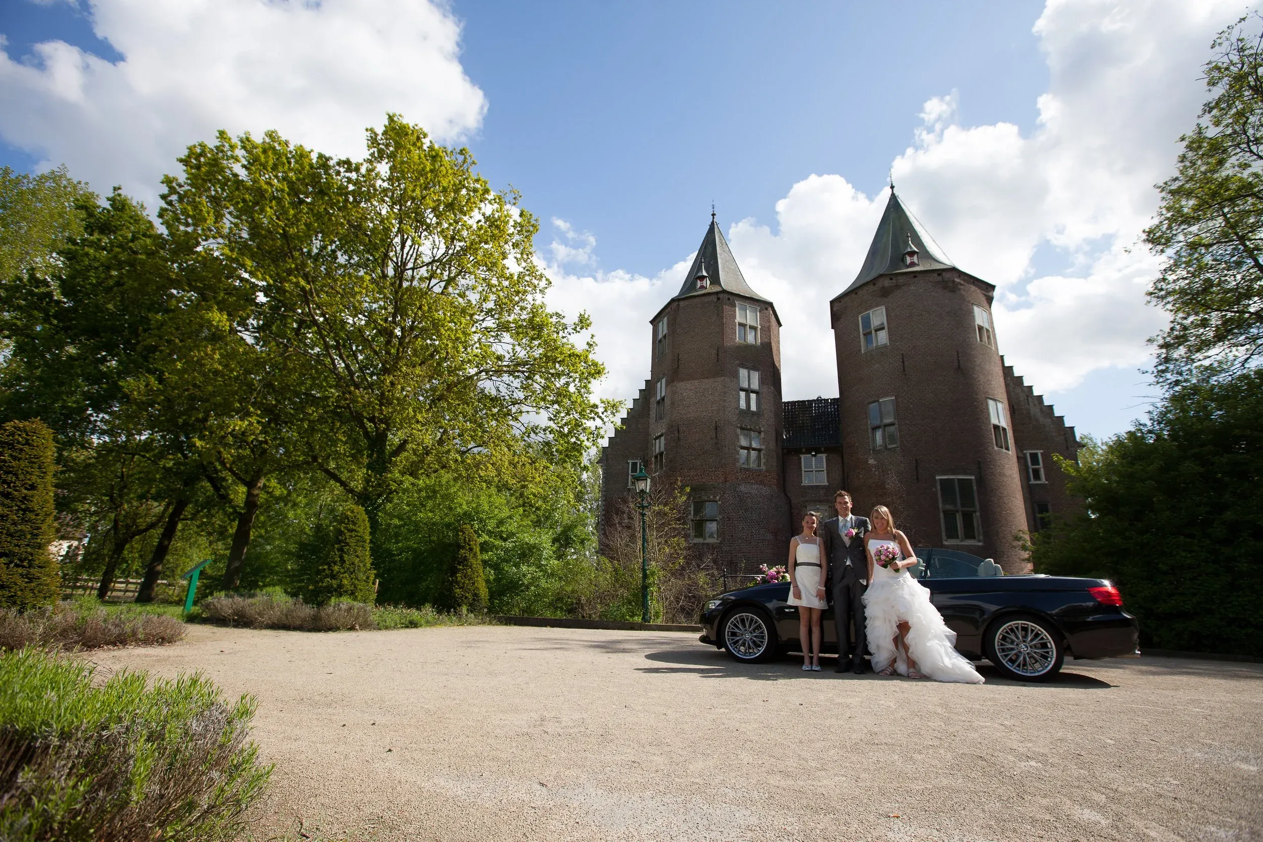 Bruidspaar bij een zwarte auto voor Kasteel Dussen met zijn twee torens
