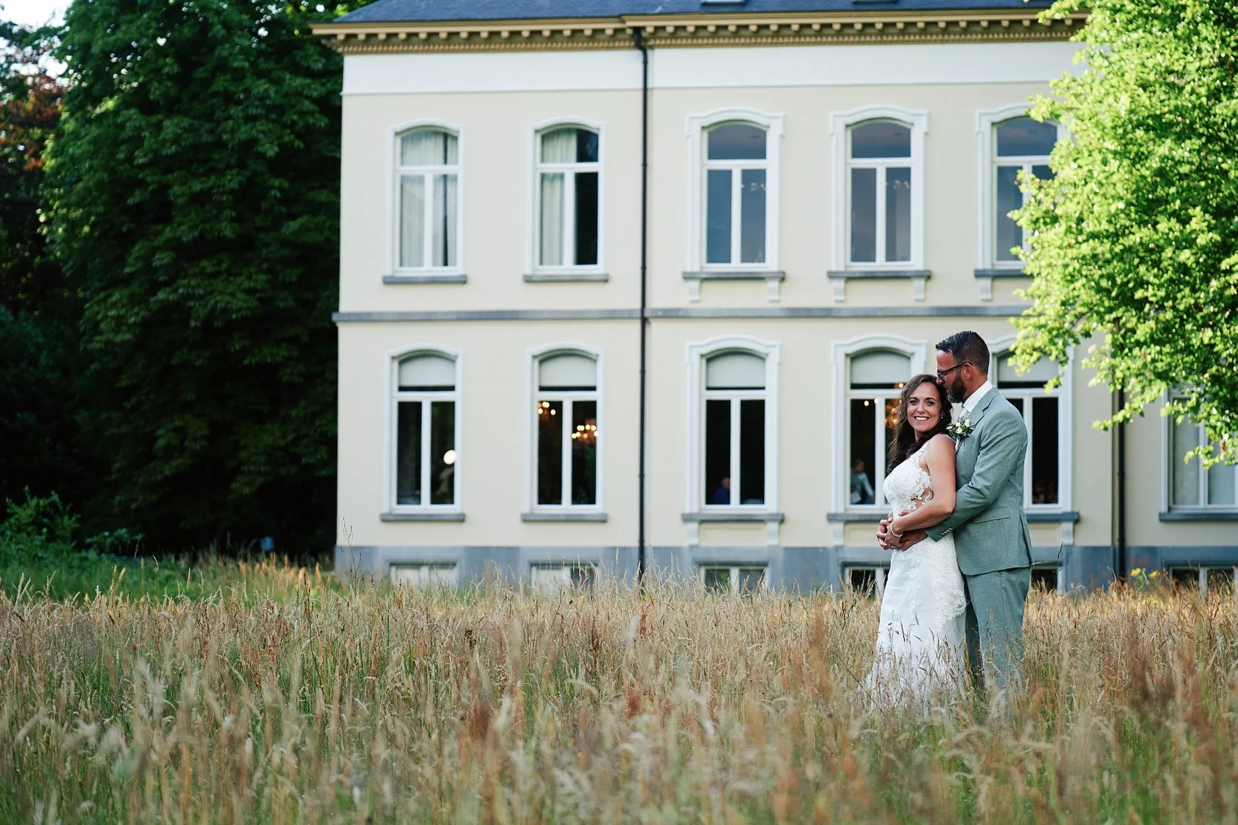 Romana en Sander in het hoge gras voor het landhuis van Landgoed Wolfslaar