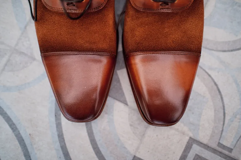 De bruine trouwschoenen van Wouter op het vloerkleed