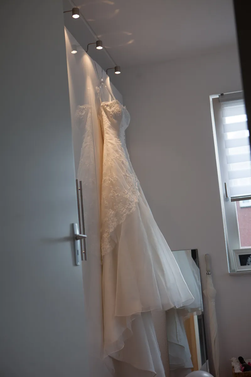 De trouwjurk hangt aan de kastdeur in de slaapkamer