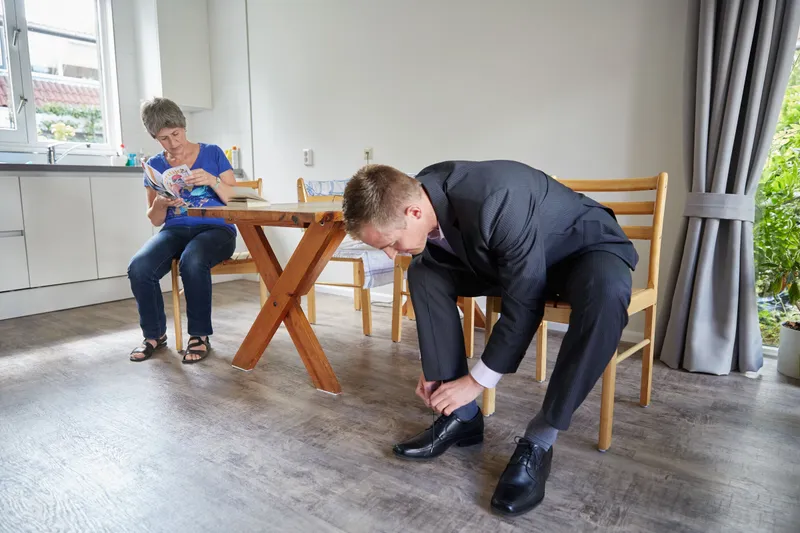 Tim trekt aan een houten tafel zijn schoen aan