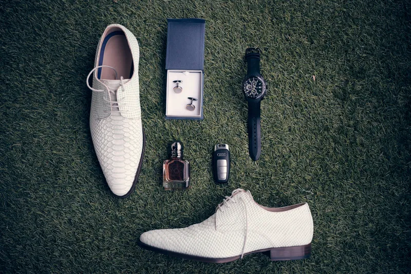 De witte schoenen, het horloge, de manchetknopen en het parfum van Dennis op het gras
