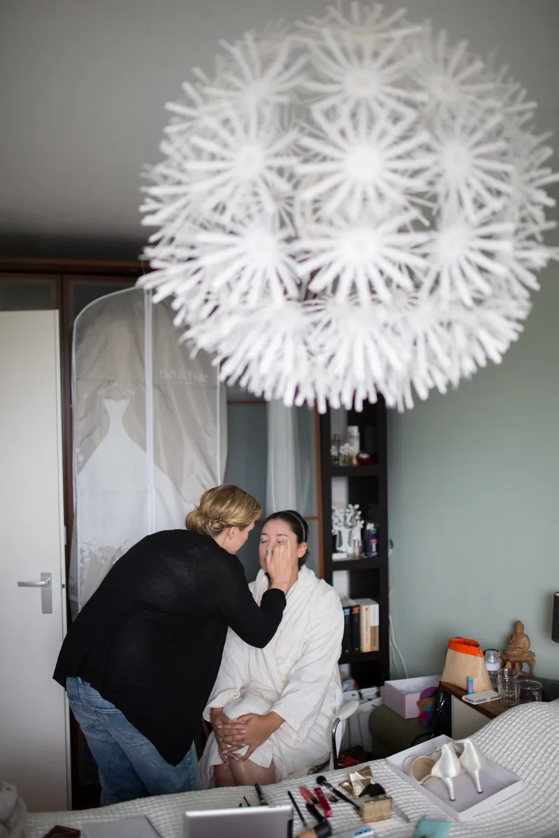 Anne-Floor wordt opgemaakt onder een witte lamp