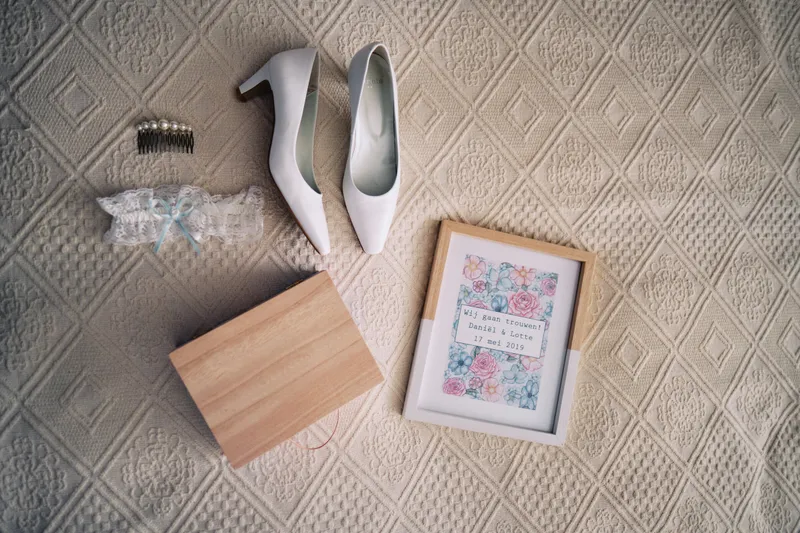Witte schoenen, sieraden en een ingelijste kaart op het tapijt