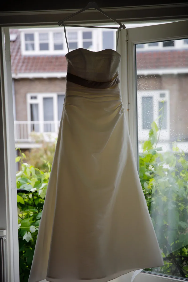De trouwjurk hangt voor het raam