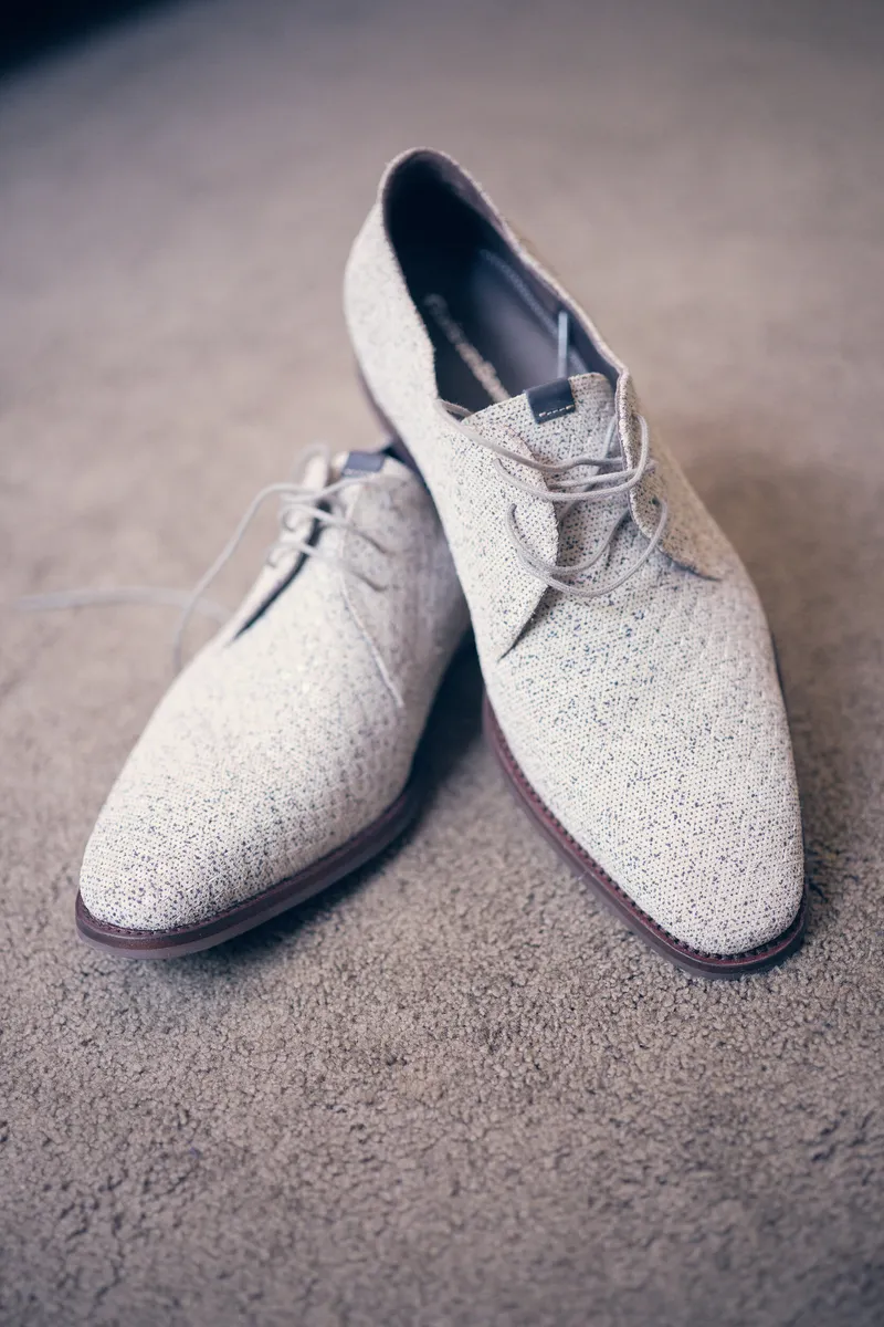 Witte trouwschoenen met een patroon op de vloer van de hotelkamer