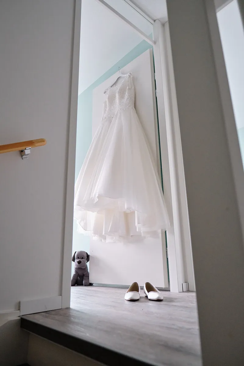 De trouwjurk hangt in de deuropening, de hond op de vloer