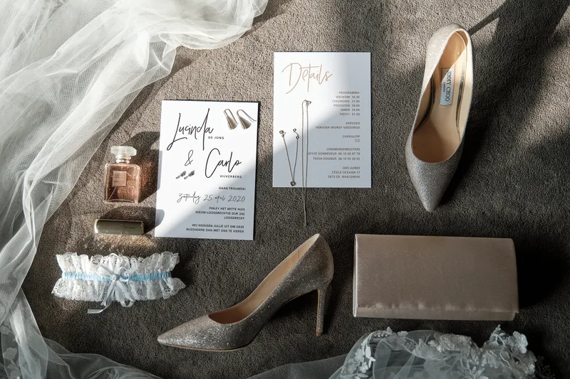 De trouwkaart, schoenen, parfum en kousenband op tafel