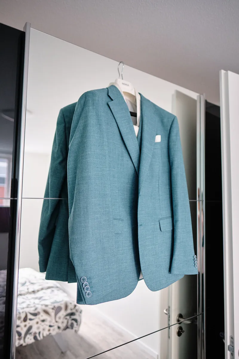Het blauwgroene colbert aan een hanger voor de spiegel