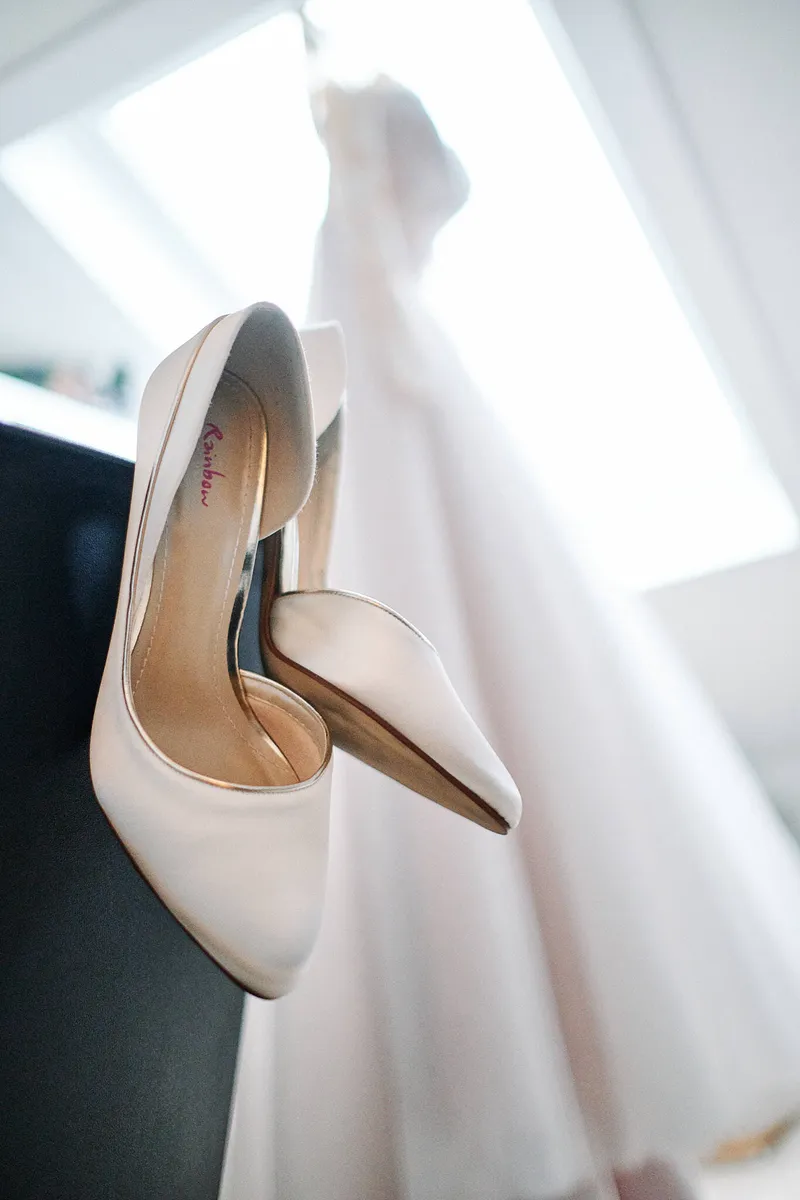 De bruidsschoenen aan de hanger van de jurk