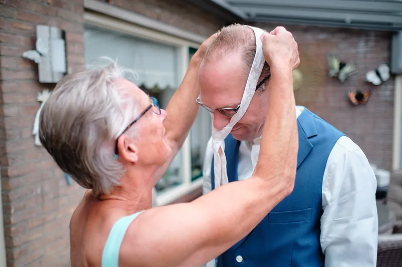De moeder van Johan doet zijn stropdas goed in de tuin