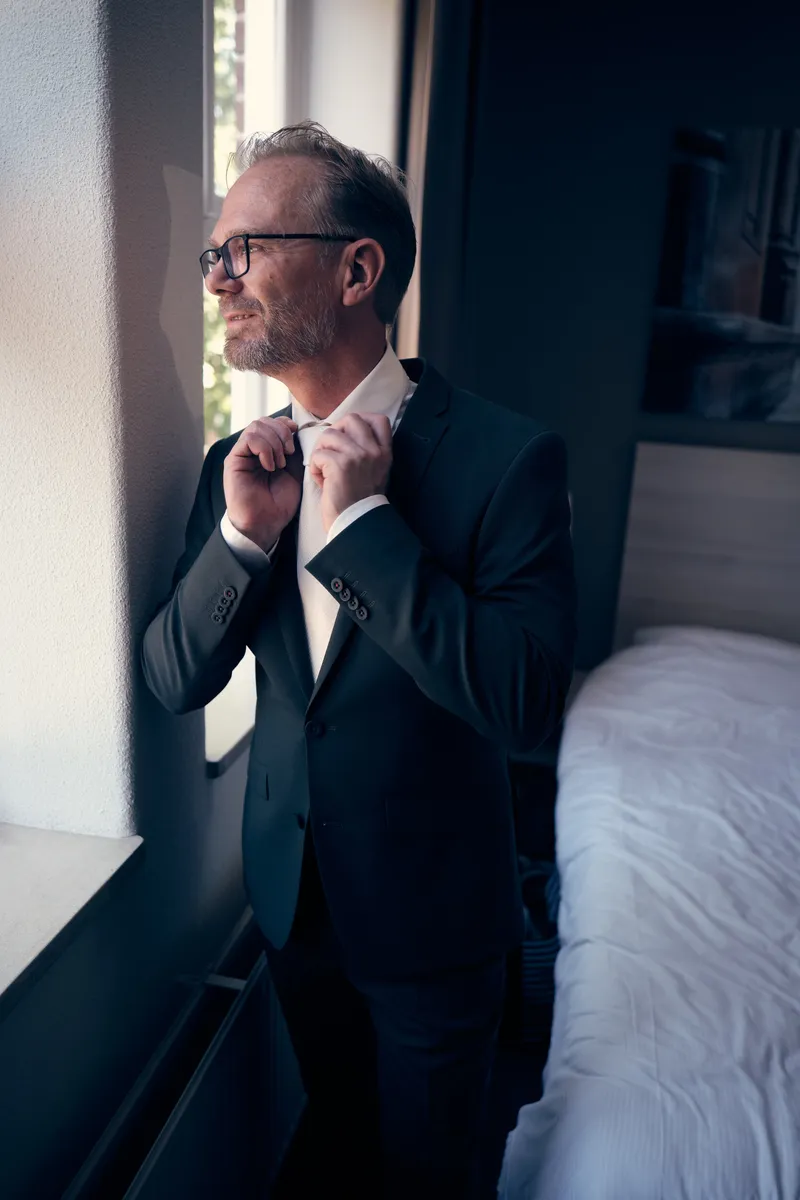 Mike doet zijn das om bij het raam van de hotelkamer