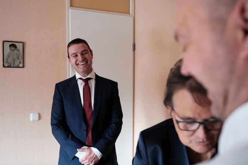 Een van de bruidegoms in zijn blauwe pak bij de deur