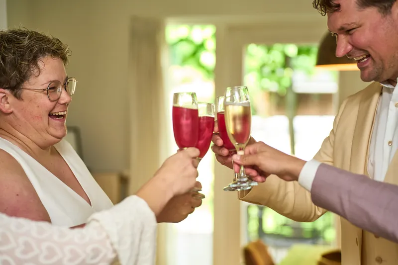 Froukje proost met een glas bubbels in de woonkamer