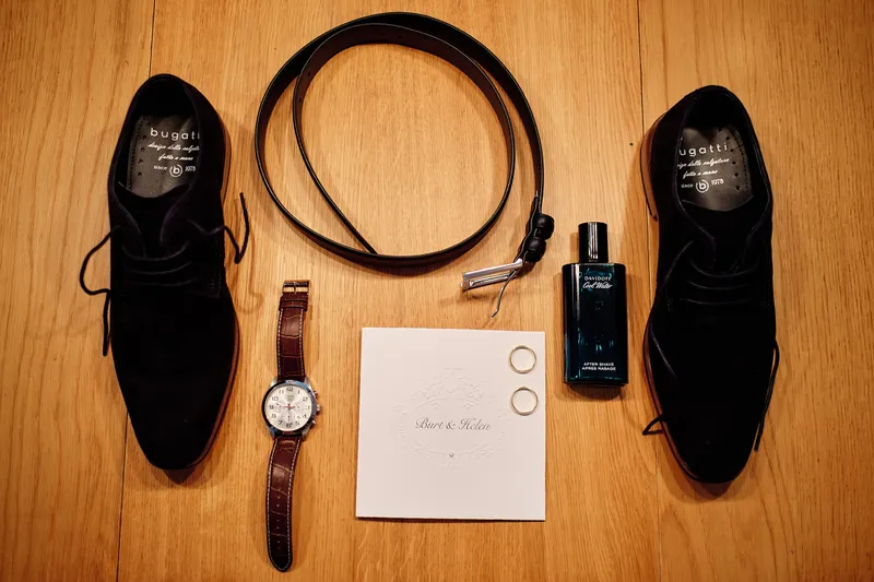 Schoenen, riem, horloge en parfum op een houten tafel