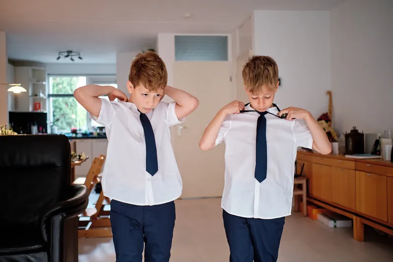 De twee zoons doen hun stropdas om