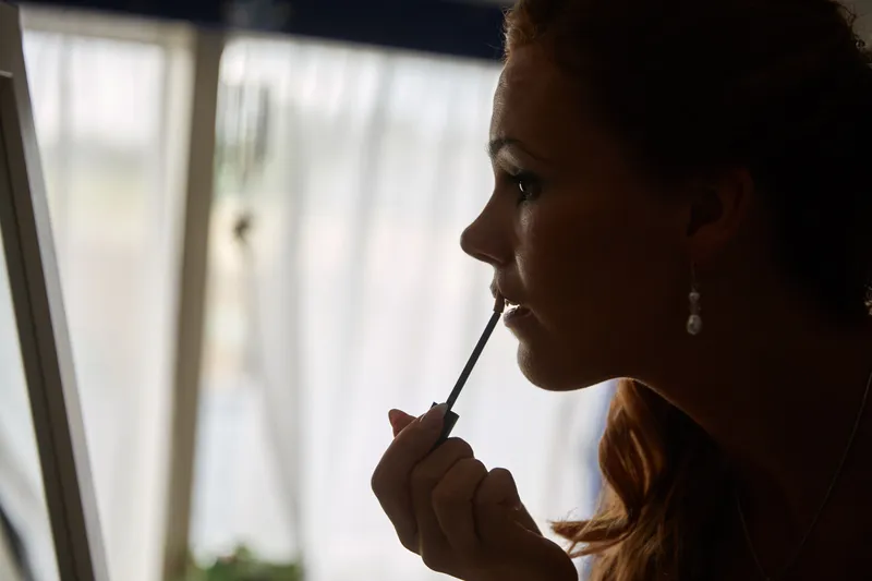 Trudy werkt haar lipgloss bij, als silhouet bij het raam