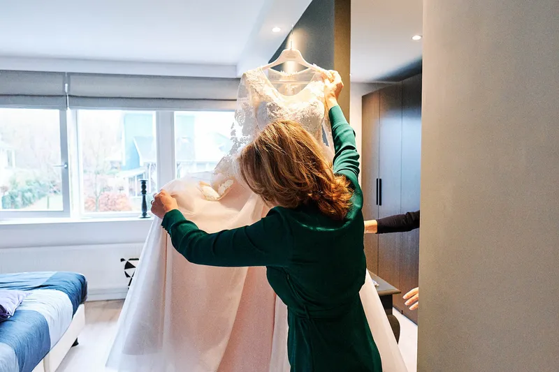 De jurk wordt klaargelegd door een vrouw in een groene jurk