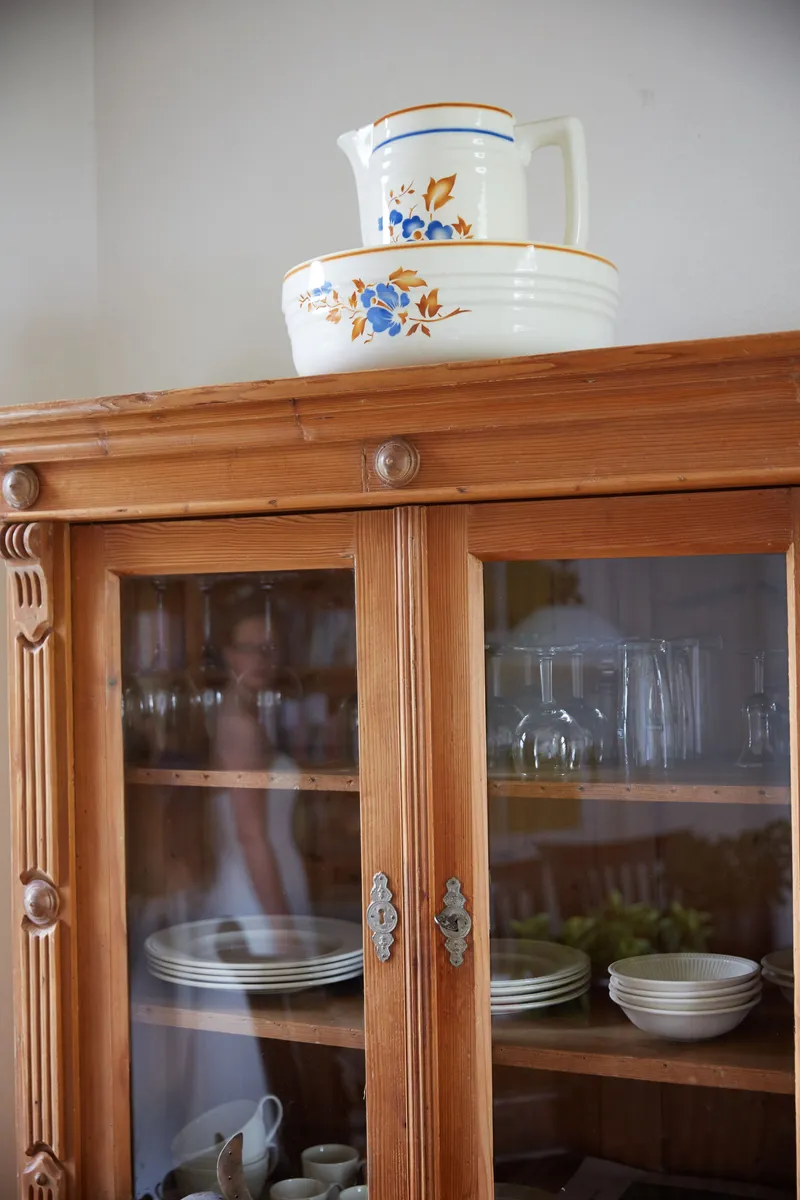 Een oude houten servieskast met een kan erop, in de boerderij