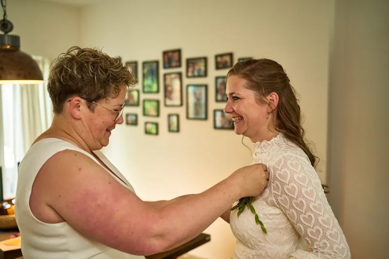 Froukje speldt een corsage op in een kamer vol ingelijste foto’s