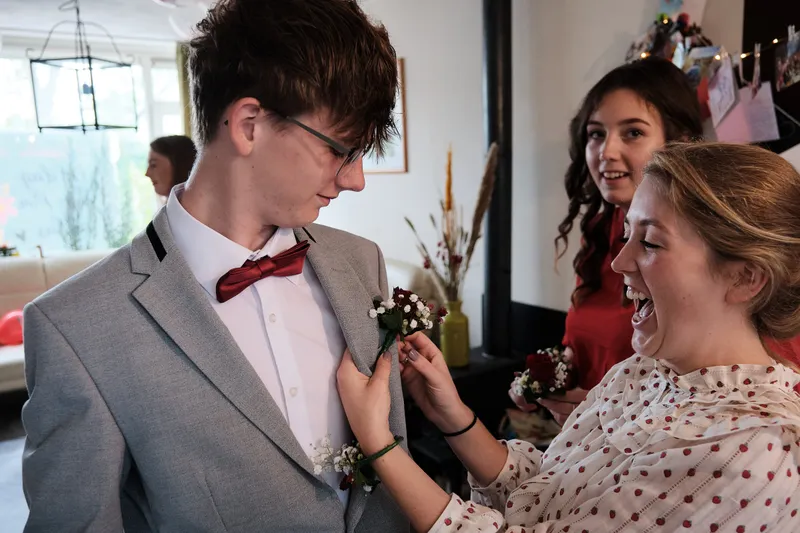 Een corsage wordt op het jasje van een van de jongens gespeld