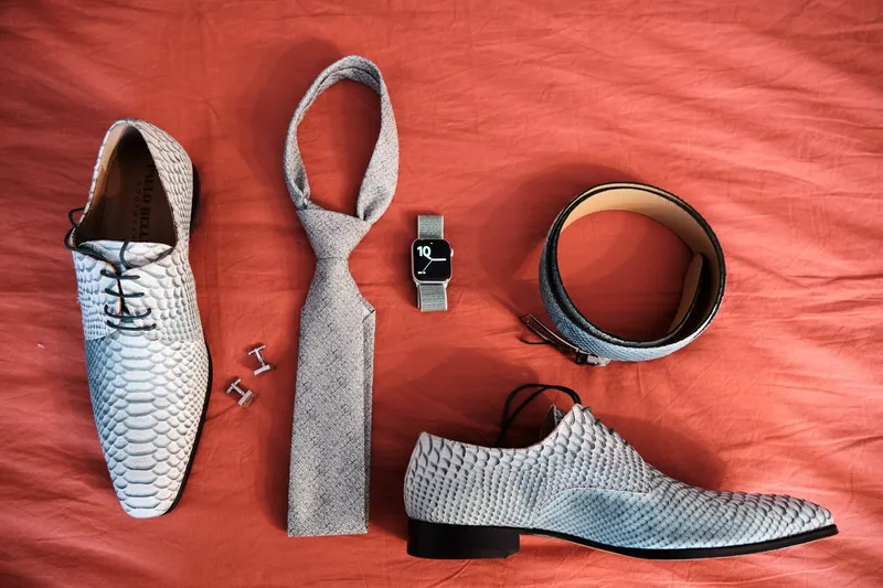Schoenen, stropdas, riem en horloge op een rode doek