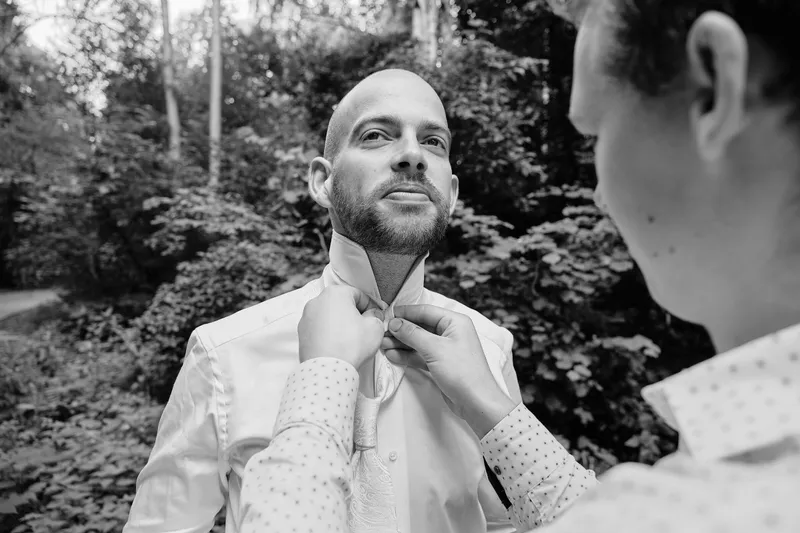 Simon knoopt zijn das in het bos, zwart-wit