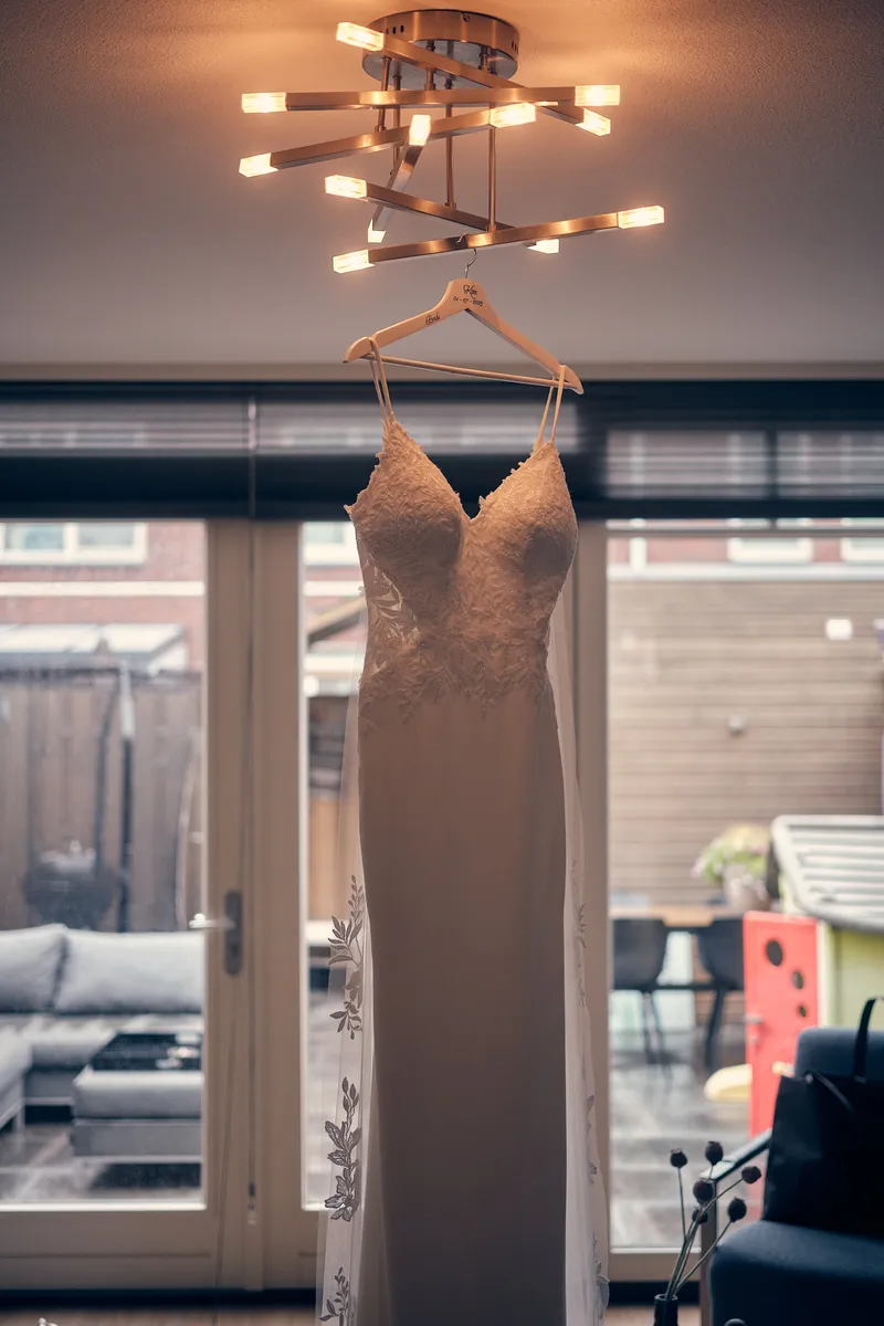 De trouwjurk hangt aan de lamp voor de openslaande deuren