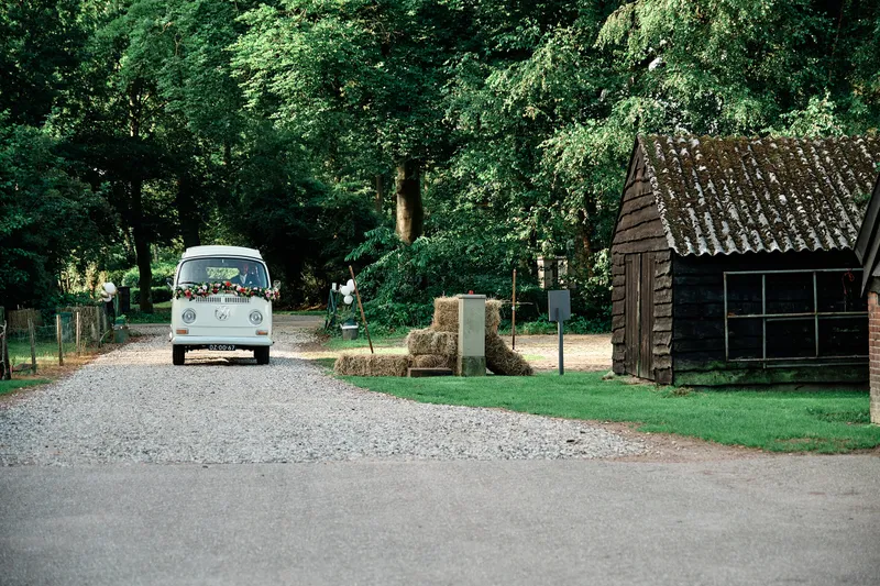 Het VW-busje rijdt over het grind tussen de bomen