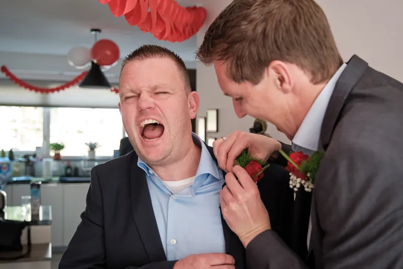 Lachen terwijl er een roos op het jasje wordt gespeld