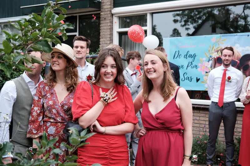 Gasten in rood en wit met ballonnen bij het huis