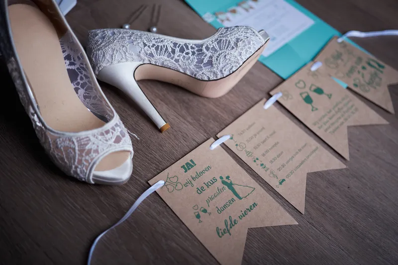 De bruidsschoenen en kaartjes met turquoise linten