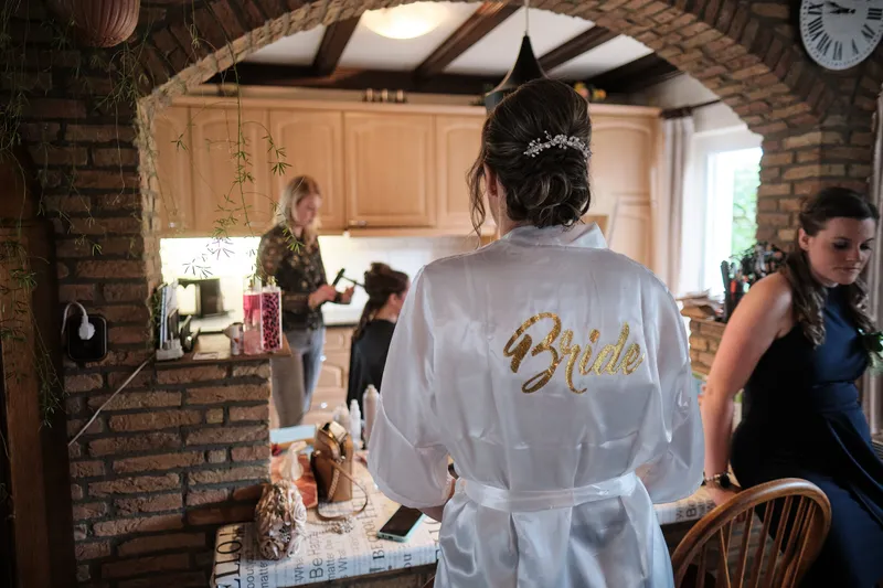 Milou in haar badjas met Bride op de rug in de keuken