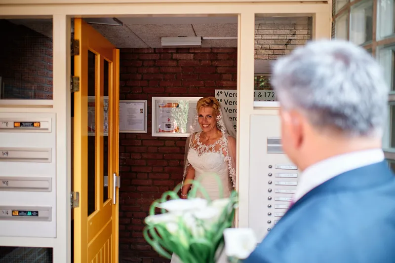 Helen met haar boeket in de gang, haar vader op de voorgrond