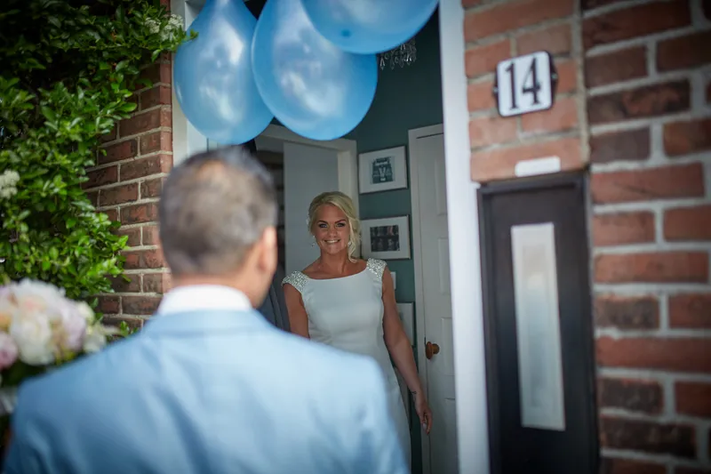 Bas staat voor de deur met nummer 14 en de blauwe ballonnen
