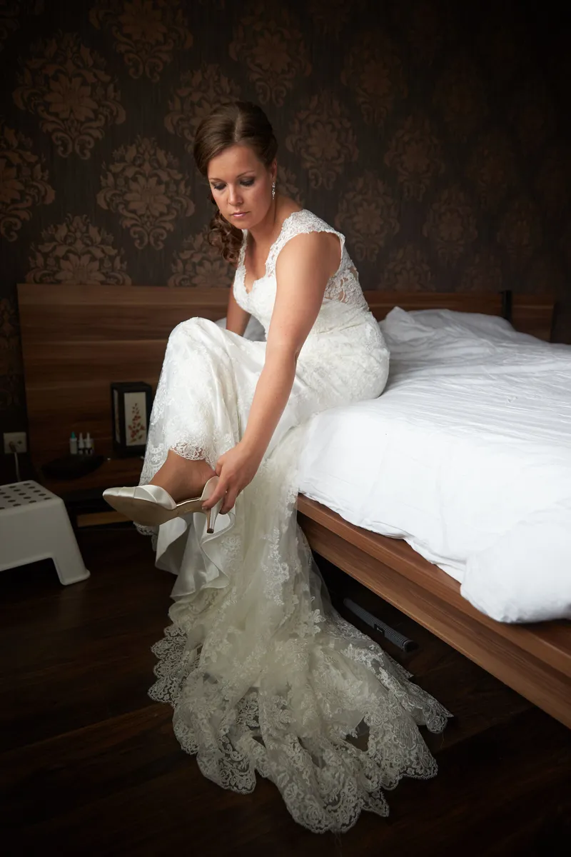 Nadine trekt op de rand van het bed haar schoenen aan