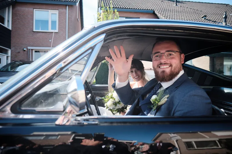 Barry zwaait vanuit de zwarte Mustang