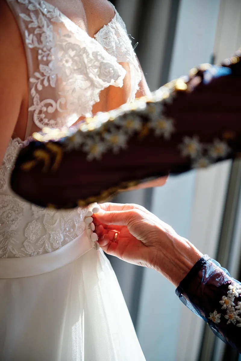 Handen maken de rug van de kanten trouwjurk dicht