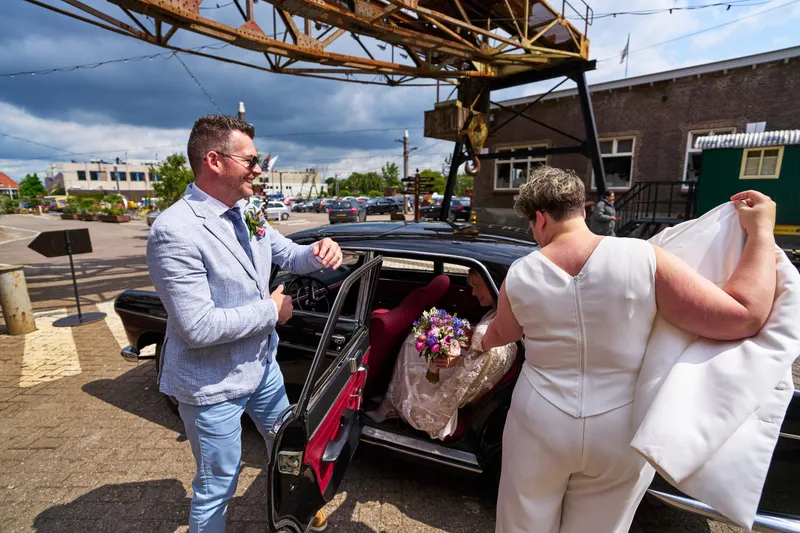 De chauffeur en Froukje laden de sleep en het boeket in de oldtimer