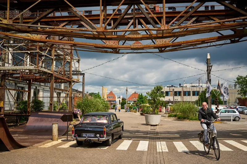 De zwarte oldtimer onder de oude kraanbaan van De Noordkade, met een fietser erlangs