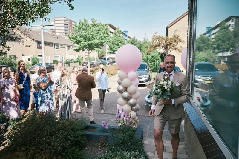 Jorg loopt met het boeket langs de ballonnen naar de voordeur