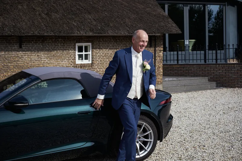 Cees stapt uit de groene sportwagen voor de boerderij