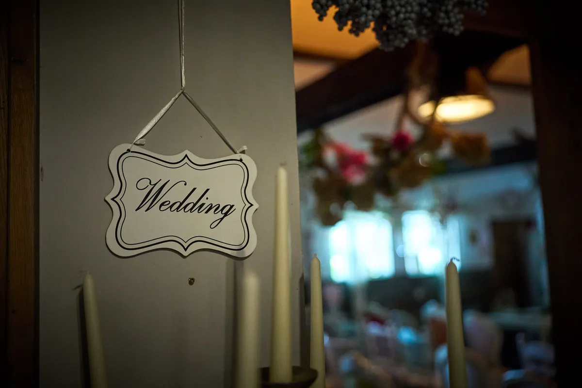 Een bordje met ‘Wedding’ bij de deur van de zaal, met kaarsen ernaast