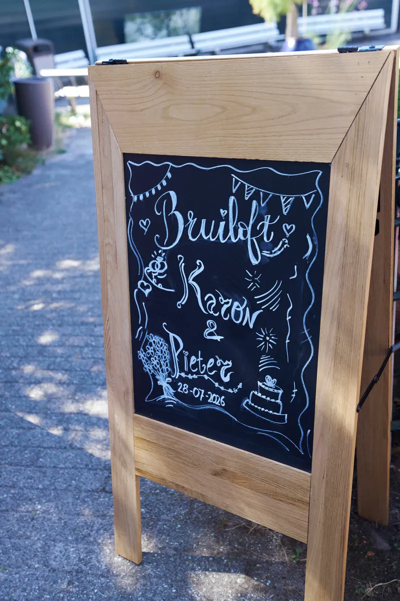 Het welkomstbord op een houten ezel bij de ingang van AA-Zicht