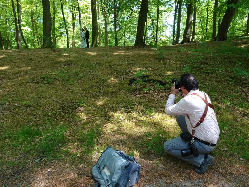 Stefan zit op zijn hurken tussen de bomen en fotografeert