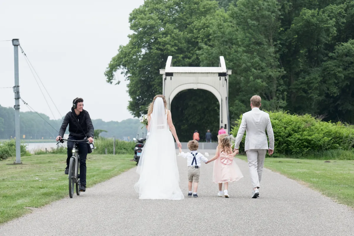 Mary, Jasper en de kinderen lopen naar de witte ophaalbrug in het Amsterdamse Bos