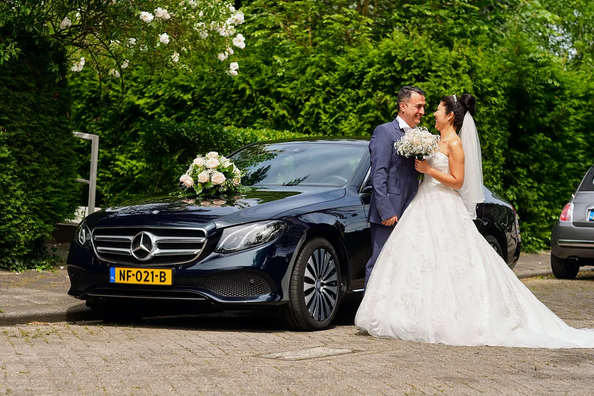 Sena en Eren bij de zwarte Mercedes met bloemen op de motorkap