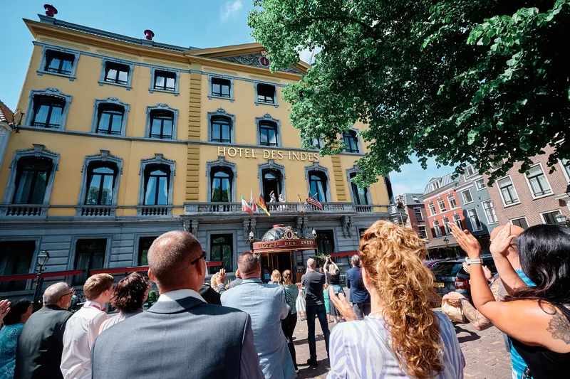 De gasten op straat voor de gele gevel van het hotel