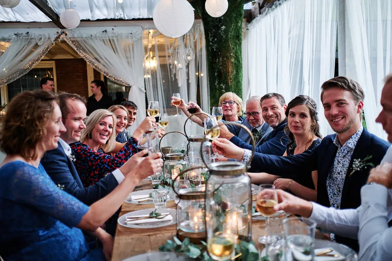 De gasten proosten aan de lange tafel